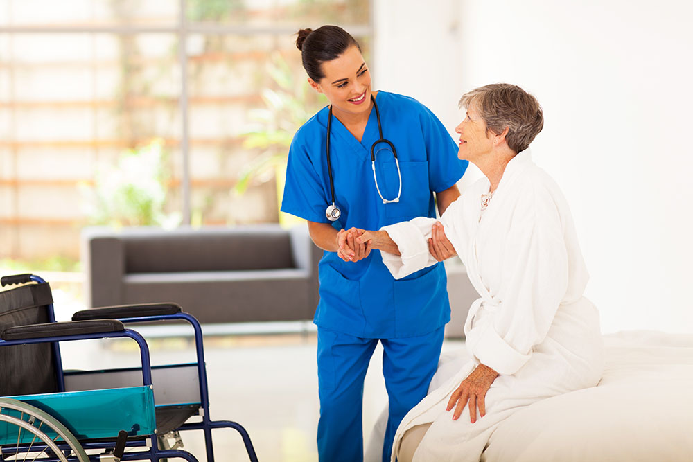 Subacute nursing care Haym Salomon Home, Brooklyn NYC. Nurse helping elderly woman stand up during post-operative wound care.