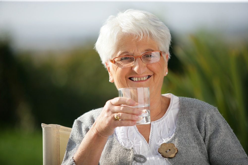 Senior woman drinking water to protect herself from heatstroke