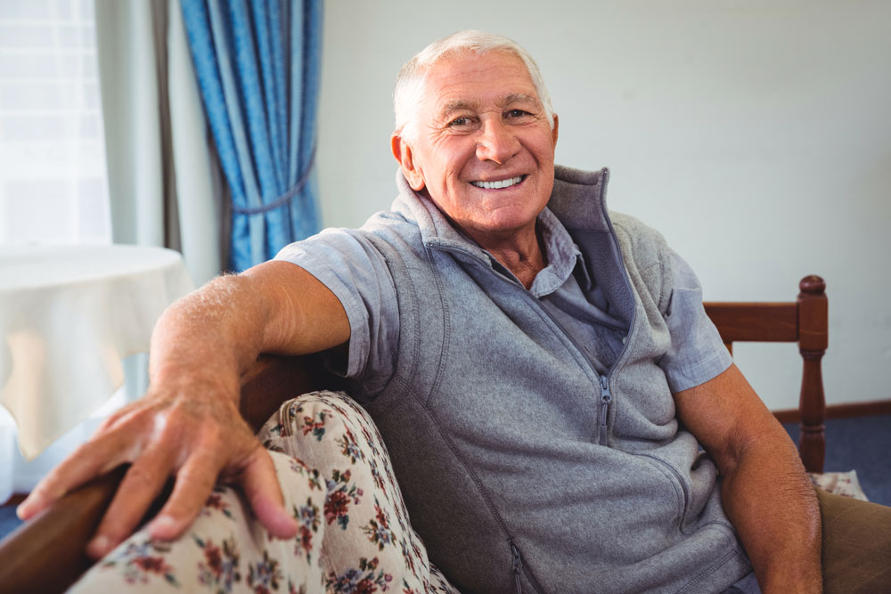 Senior man sitting on couch enjoying long-term nursing care