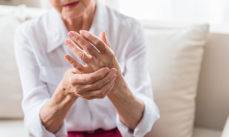 Elderly woman massaging her hand to reverse rheumatoid arthritis