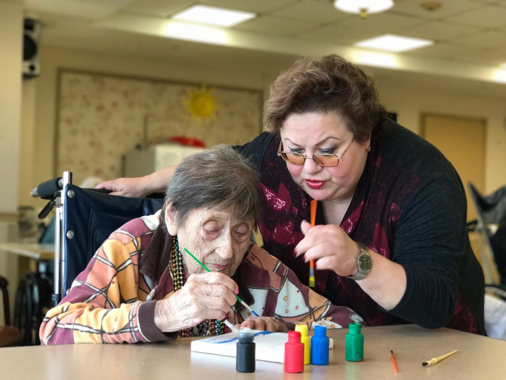 Elderly women painting as a part of dementia long term care at Haym Salomon Home