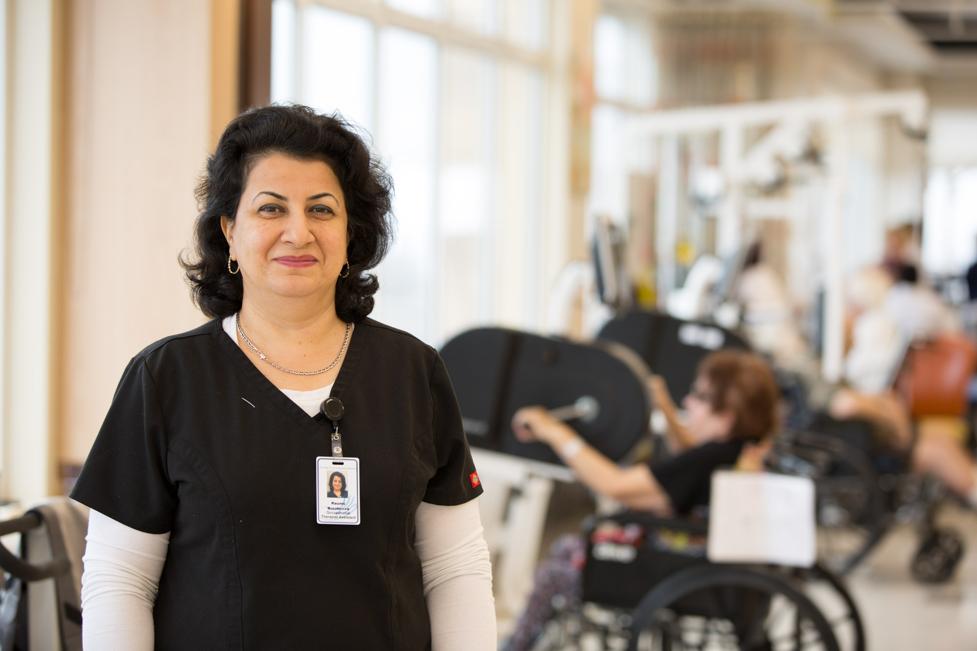 Portrait of Haym Salomon rehab staff with people on background getting rehab therapy to stay safe and healthy