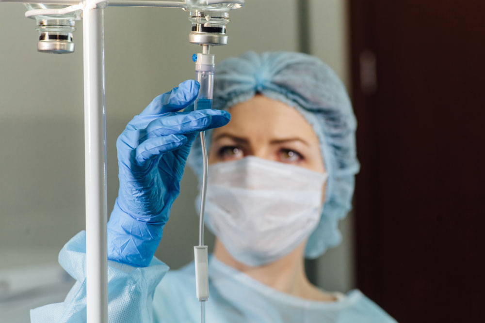 Nurse injecting IV fluids for the patient