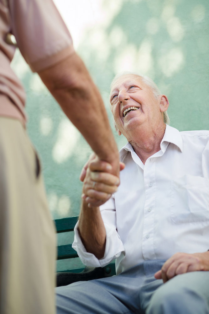 Elderly man happily shaking hands with rehabilitation staff after doing stress busting activities