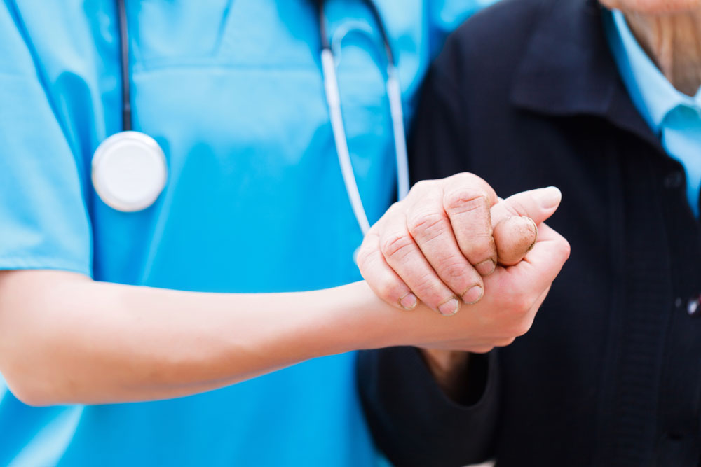 Caring nurse holding elderly hands nursing home