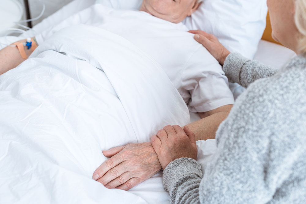 Senior women holding hand of her husband who is suffering from mild stroke