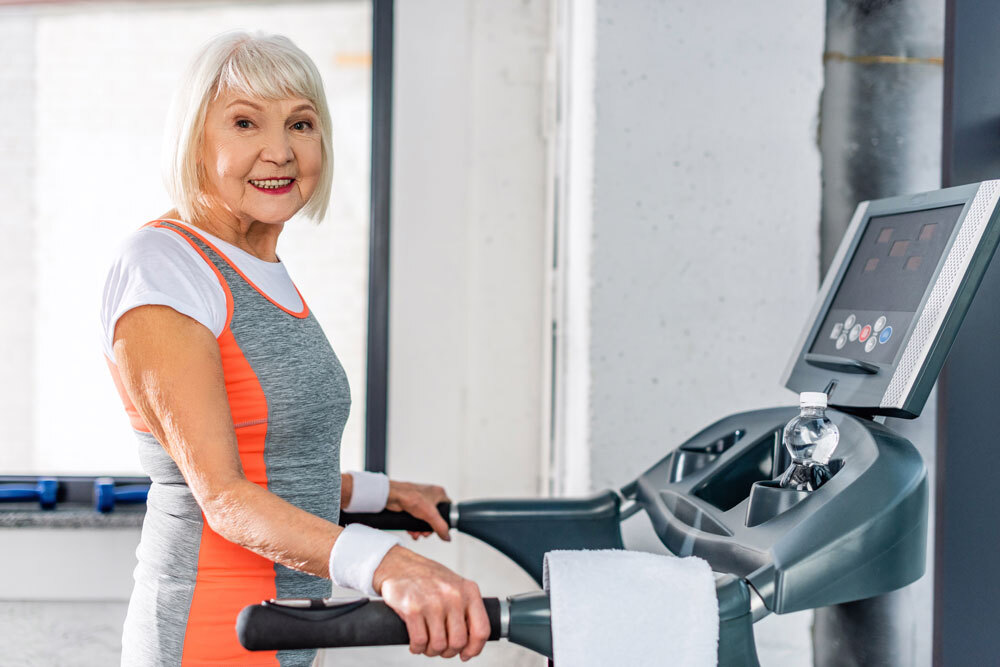 Happy elderly women doing exercise on treadmill machine to avoid bone loss and multiple sclerosis