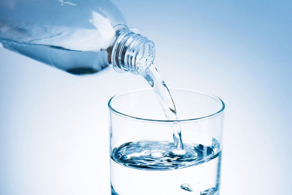 Pouring water in glass from bottle to keep hydrated and avoid allergy triggers