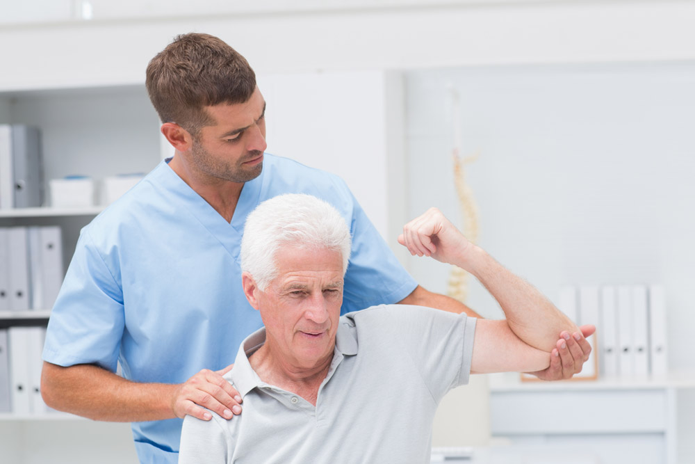 Therapist helping senior man with shoulder disorders