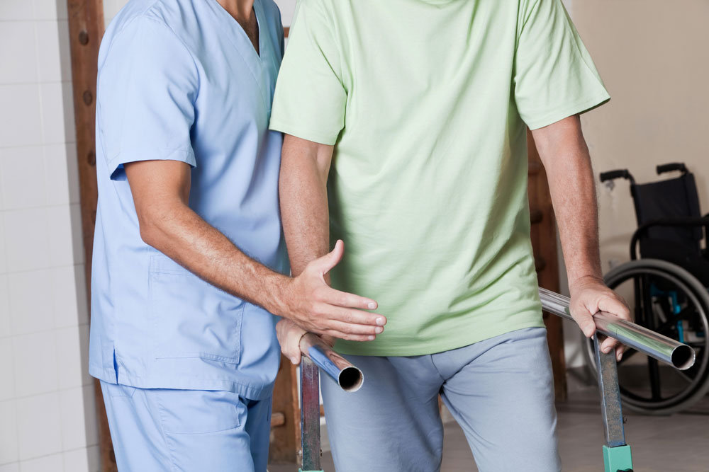 Nurse providing restorative therapy to an elderly man suffering from neurological diseases