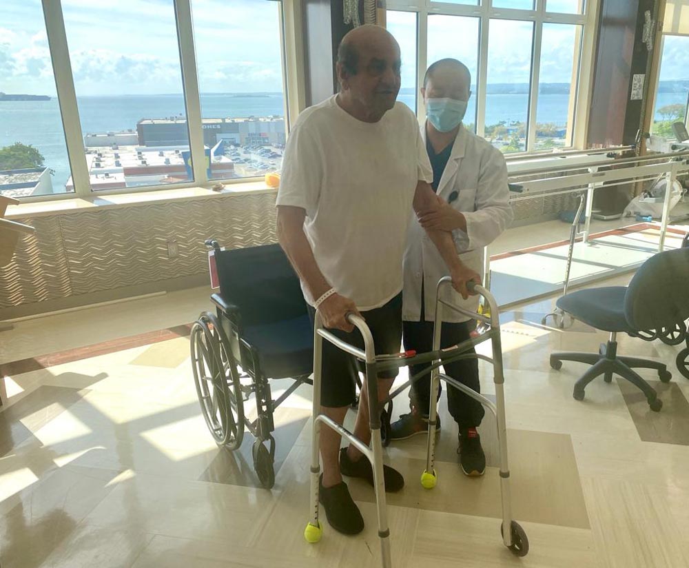 Physical therapist helping elderly man recovering from hip surgery to walk