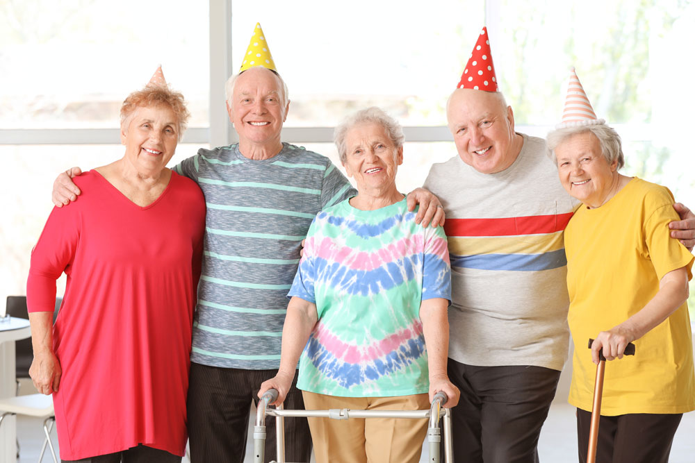 Happy senior people enjoying birthday party in a nursing home as a part of recreation therapy to improve their health