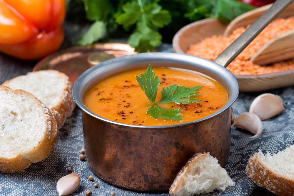 Red lentil soup with pepper and spices in a copper saucepan - Best warming foods for cold winter days.