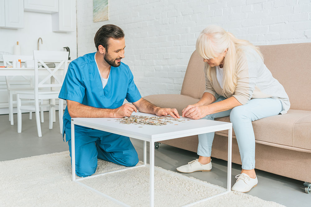 Therapist helping senior woman with puzzle games during memory activities session.