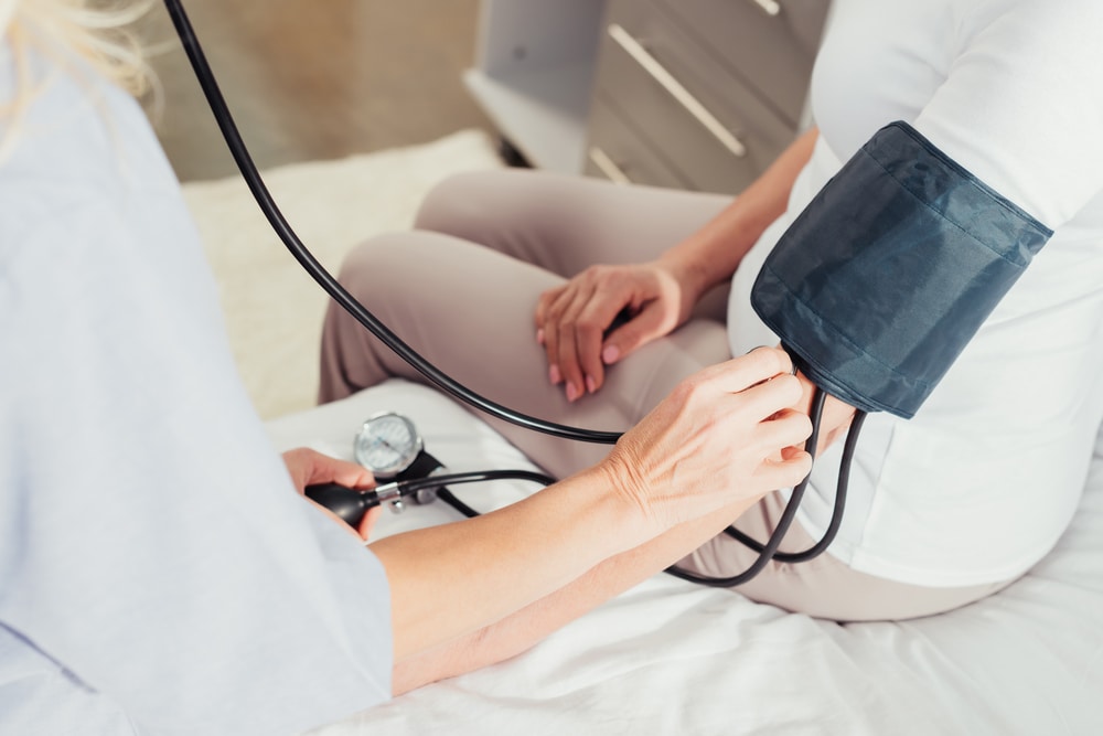 Nurse checking blood pressure of a woman as part of regular rehab after a hospital stay.