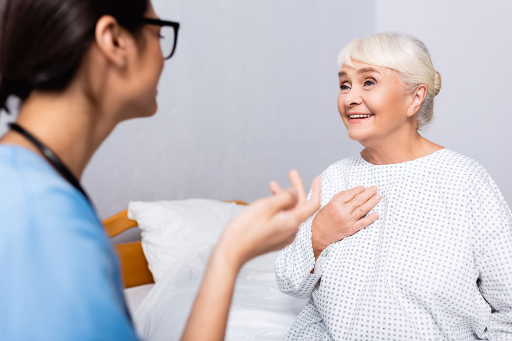 Elderly woman touching chest while talking to the nurse during swallowing exercises therapy session