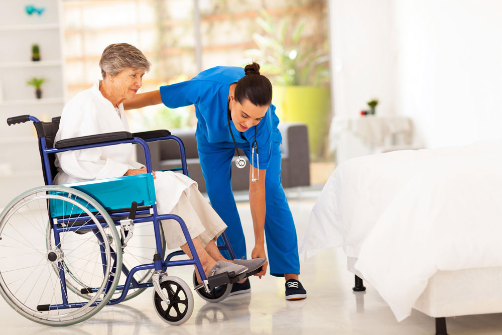 Nurse helping elderly woman with fractured hip to sit on a wheelchair