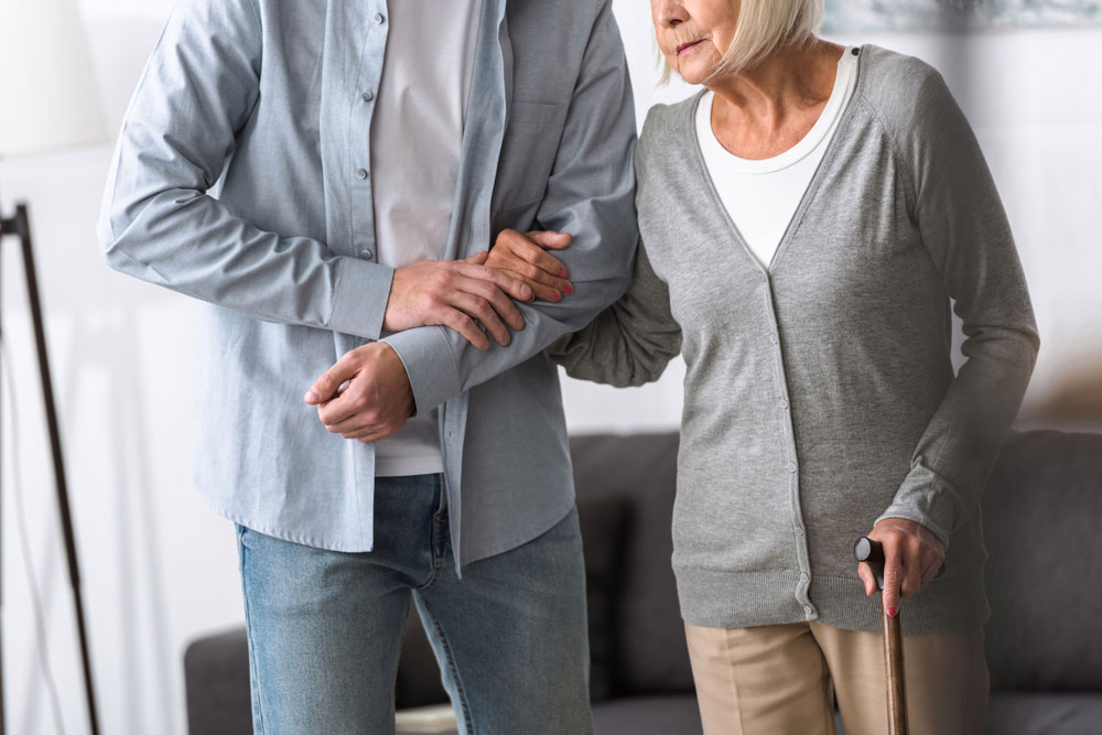 A person helping a senior woman with mobility loss