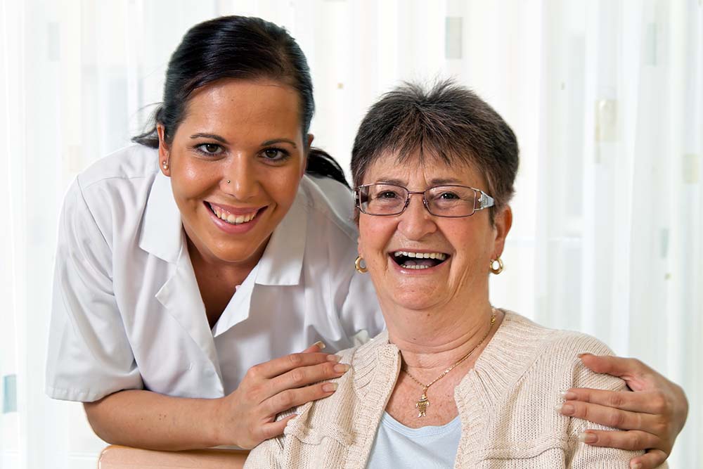 Nurse holding shoulders of a smiling patient going through memory rehab