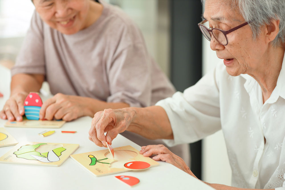 Happy asian senior woman playing puzzle as brain games to help with dementia.