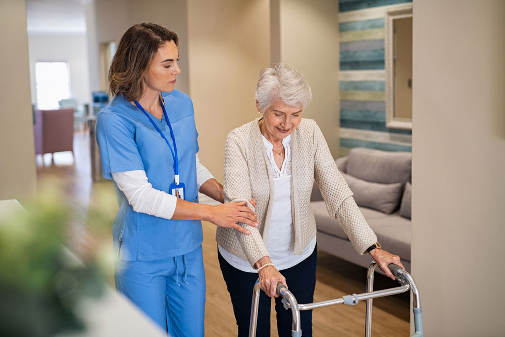 Nurse helping an elderly woman in walking as part of physical therapy after an accident to prevent neuropathy from spreading.