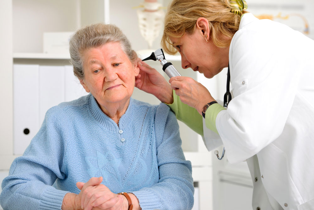 Female ENT specialist checking ear of an old woman suffering from inner ear problems.