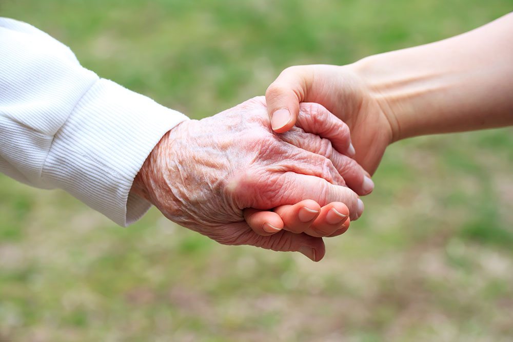 Elderly man and woman with signs of neurological problems holding hands.