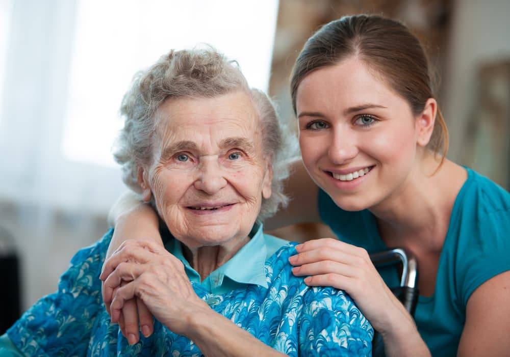 Nurse taking care of happy elderly woman gong through heart stent recovery time.