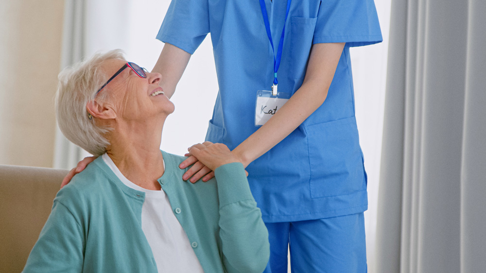 Therapist hugging smiling mature grey haired lady after physical therapy session to prevent triggers of arthritis pain.