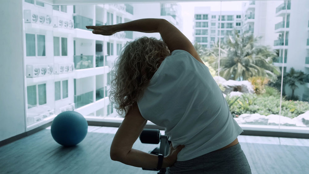 Elderly woman doing squatting exercises in the gym to prevent causes of joint destruction.