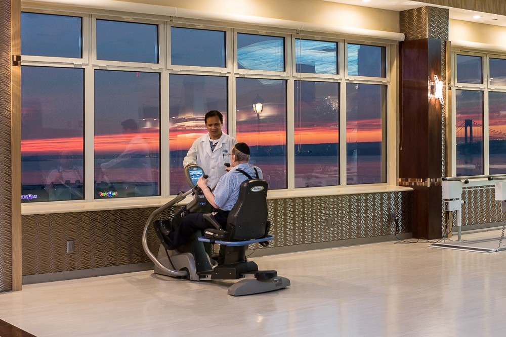 Doctor supervising senior man on recumbent bike during sunset, illustrating how the heart thrives on regular exercise
