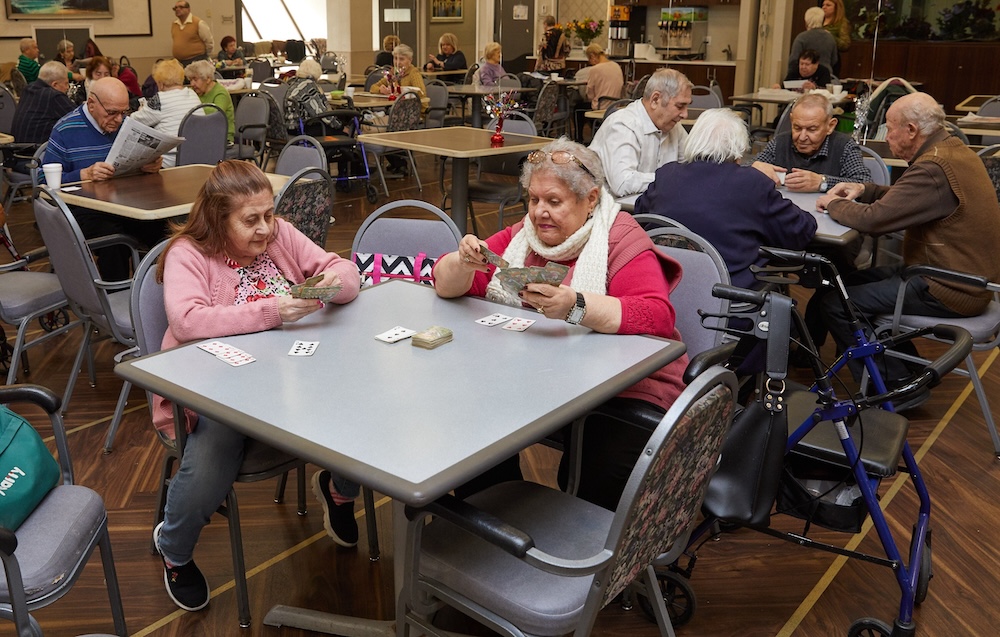 Activities Independence Group of seniors playing cards together in a community center, promoting activities independence and social engagement among older adults.